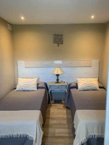 a bedroom with two beds and a table with a lamp at La Casina de Martín in Limanes