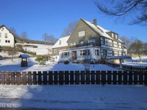 una casa grande con una valla en la nieve en Pension Haus zur Orke, en Winterberg