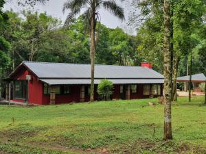 ein rotes Haus mitten auf einem Feld mit Bäumen in der Unterkunft la escondida in Puerto Leoni