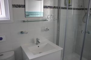 a white bathroom with a sink and a shower at The Elmfield in Great Yarmouth