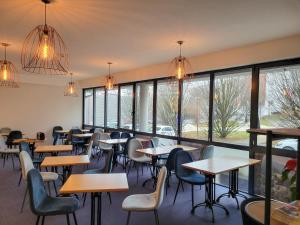 a restaurant with tables and chairs and windows at B&B HOTEL Rodez Bourran in Rodez