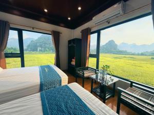 ein Schlafzimmer mit zwei Betten und einem großen Fenster in der Unterkunft Trang an rice field homestay in Ninh Bình