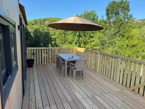 a wooden deck with a table and an umbrella at Baraca lu Max in Cuptoare +2 photos