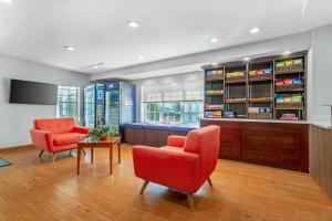 a living room with two chairs and a table and a tv at MainStay Suites Tampa Moffitt-USF in Tampa