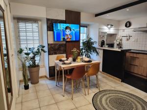 a kitchen with a table with chairs and a tv on the wall at Appartement a Millau in Millau