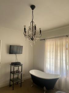 a bath tub in a room with a chandelier at Boschberg Cottage in Somerset East