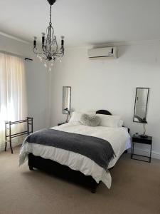 a white bedroom with a large bed and a chandelier at Boschberg Cottage in Somerset East +14 photos