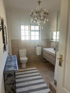 a bathroom with a toilet and a sink and a chandelier at Boschberg Cottage in Somerset East +15 photos