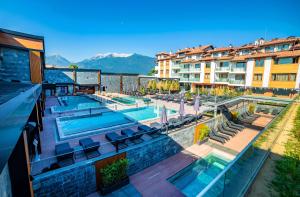 a hotel with a swimming pool with mountains in the background at Grand Hotel Bansko - Fitness & SPA in Bansko