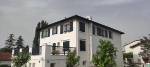 ein weißes Gebäude mit schwarzen Fenstern und einem Balkon in der Unterkunft Gîte Larrun Lodge in Sare