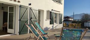 zwei Schaukelstühle auf einer Veranda neben einem Gebäude in der Unterkunft Gîte Larrun Lodge in Sare