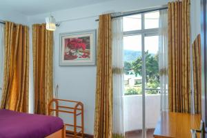 a bedroom with a bed and a window with curtains at Mountain Breeze Cool Apartment in Nuwara Eliya