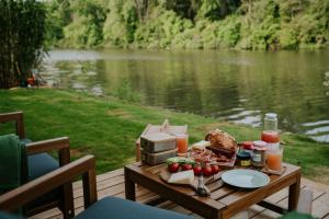 a table with food and drinks on a table near a lake at Feelmore Tiny House Szarvas in Szarvas +1 photo