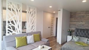 a living room with a gray couch and a wooden wall at Apartamentai su balkonu prie Akropolio Taikos pr 48 in Klaipėda