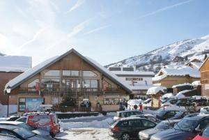 圣索林达尔沃Charmant appartement 4 personnes Centre station的一座大楼，车停在雪地里