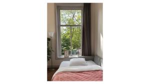 ユトレヒトにあるIn de Pastorie Utrecht - Old rectory, just steps away from the city centerのベッドと窓のある寝室