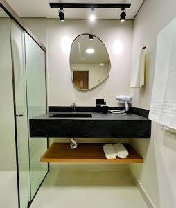 un baño con lavabo y espejo en Confortável Flat no Centro, en Londrina