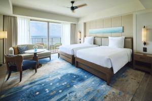 una habitación de hotel con dos camas y una silla en ANA InterContinental Ishigaki Resort by IHG, en Ishigaki Island