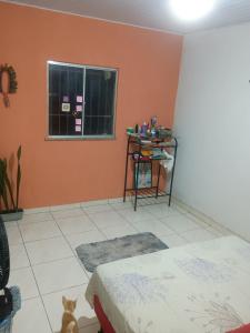 a room with a bed and a cat sitting in front of a window at Casa na floresta cósmica in Ananindeua