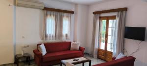 a living room with a red couch and a tv at Sunset Seaview Apartment in Ladochórion