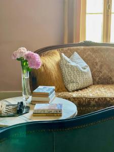 Una mesa de café con libros y flores en un sofá. en Chambre D'hôtes Maison Avenue Mondenard, en Nérac