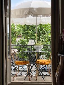 Un balcón con una mesa y sillas y una sombrilla. en Chambre D'hôtes Maison Avenue Mondenard, en Nérac