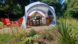 a tent with a table and chairs in a garden at Tente insolite en pleine nature in Tréduder