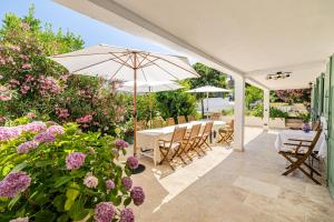 a patio with a table with an umbrella and flowers at LA VILLA DES FLEURS en duplex avec jardin et piscine in Le Cannet