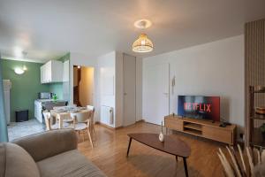 un salon avec un canapé et une télévision dans l'établissement 10min de Disney Duplex 2ch avec Parking & Balcon, à Bailly-Romainvilliers