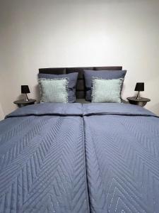 a bed with a blue comforter and two lamps at Metropolitan am Schloßpark in Paderborn