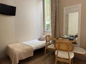 a small room with a bed and a table and a window at Nice Garden Hotel in Nice