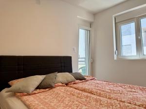 a bedroom with a bed with a orange comforter and two windows at Mirabela Apartman Sokobanja in Soko Banja +20 photos