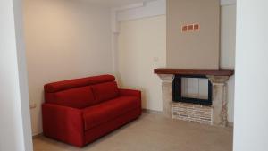 a red couch in a living room with a fireplace at Casa Pie' di Monte Refuge in Bisegna
