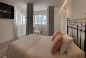 ein Schlafzimmer mit einem Bett mit weißen Laken und Kissen in der Unterkunft Cantábrico Fonsagrada in A Fonsagrada