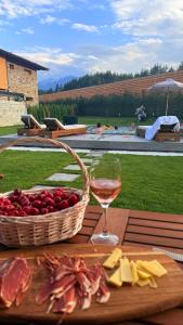Una cesta de queso y una copa de vino en una mesa en Solis Thermal Villas- HOT pool, en Banya