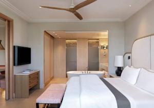 a bedroom with a bed and a tub and a television at The Westin Resort, Costa Navarino in Romanu