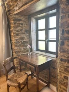 einen Holztisch und einen Stuhl in einem Zimmer mit Fenster in der Unterkunft Cantábrico Fonsagrada in A Fonsagrada
