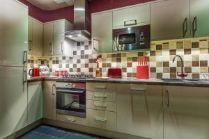 a kitchen with white cabinets and a microwave at Silversprings - City Centre Apartments with Parking in Exeter
