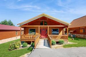 a log home with a red door and a yard at Southern Comfort Cabin By Avada Properties in Gatlinburg