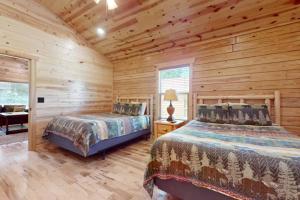 a bedroom with two beds in a log cabin at Southern Comfort Cabin By Avada Properties in Gatlinburg +23 photos
