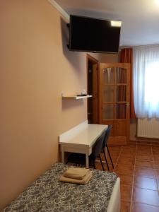 a room with a bed and a desk and a television at Karpatia Esztergom in Esztergom