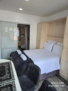 a bedroom with a large white bed and a chair at 4 logements à La Trinité proche de Nice 15 mn, Monaco 20 mn et l'Italie 30 mn 2 Chambres et 2 Studios privés et indépendants in La Trinité