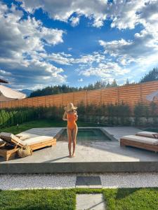 Una mujer en bikini naranja parada junto a una piscina. en Solis Thermal Villas- HOT pool, en Banya 47 fotos más