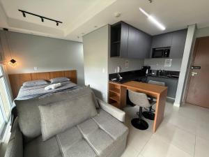 a bedroom with a bed and a desk and a kitchen at Apartamento 75 - Aconchegante in Ribeirão Preto