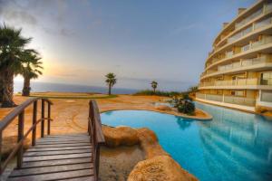 a swimming pool next to a building with a resort at Hal Saghtrija E7 in Żebbuġ