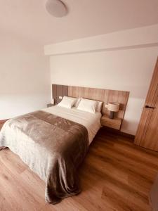 a bedroom with a large bed with a wooden headboard at A Academia in Vimianzo