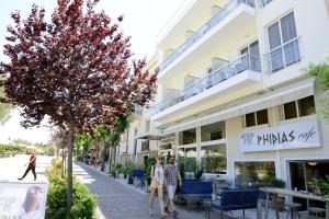 two people walking down a street in front of a building at Phidias Hotel in Athens