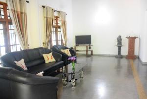 a living room with a black couch and a tv at Bawana Luxury Bungalow in Anuradhapura