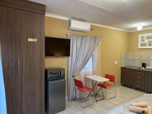 a kitchen with a table and chairs and a table and a counter at Nkandla Yethu Guest House in Nelspruit