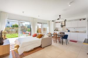 a bedroom with a bed and a kitchen with a table at Bel appartement avec jardin proche des plages in Anglet